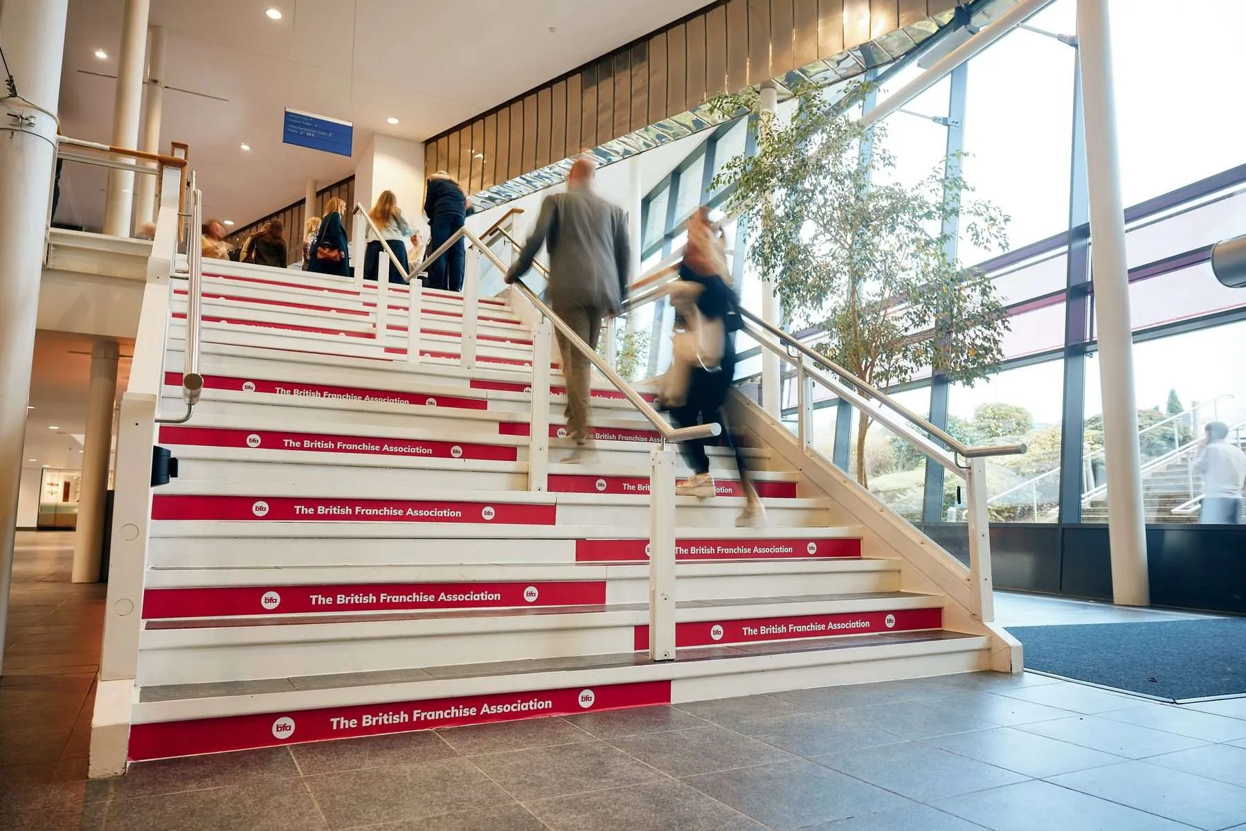 Delegates walking up The British Franchise Association branded staircase at the BFA Annual Conference
